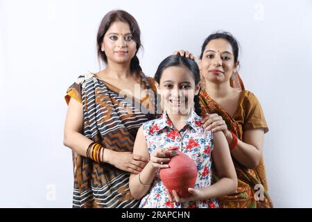 Happy rural Indian villager family of women saving money for future in piggy bank. Aspirational lady showing saving money concept. Stock Photo