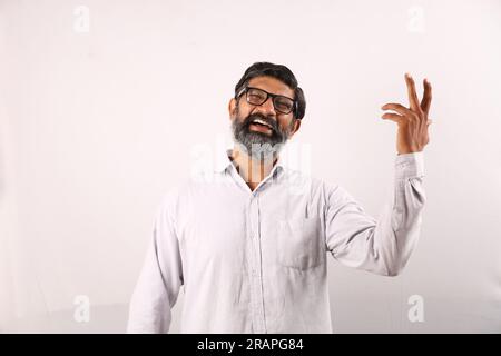 Portrait of Indian bearded man wearing shirt. Funky expressions portraying sense of accomplishment and achievement. Feeling proud of executing things. Stock Photo