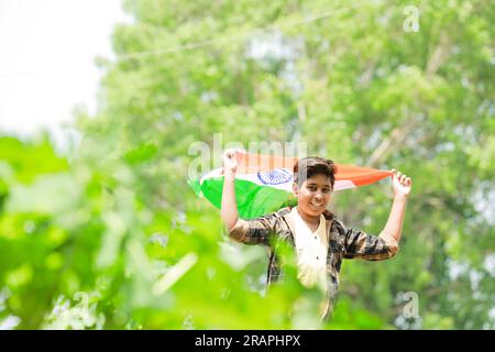 Indian boy holding national flag in farm, happy boy, national flag, poor kids Stock Photo