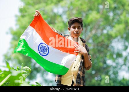 Indian boy holding national flag in farm, happy boy, national flag, poor kids Stock Photo