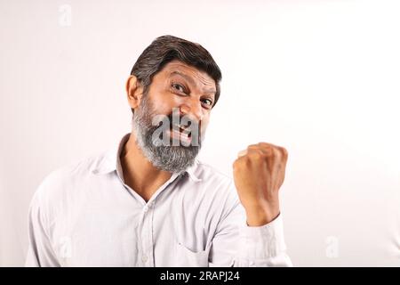 Portrait of Indian bearded man wearing shirt. Funky expressions portraying sense of accomplishment and achievement. Feeling proud of executing things. Stock Photo