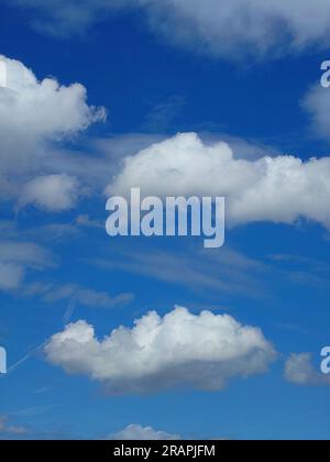 White puffy clouds set against a deep blue summer sky. Stock Photo