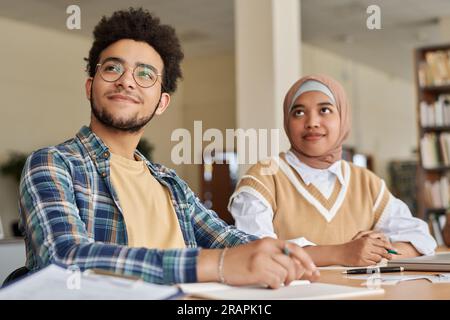 Foreign students studying languages while sitting at table with textbooks in class Stock Photo