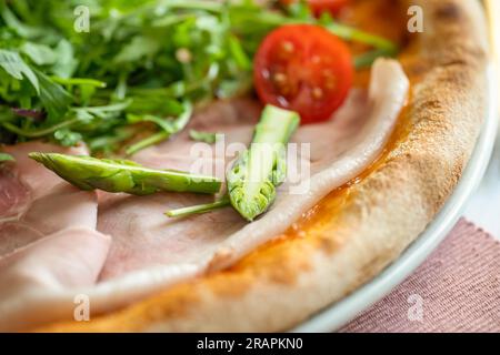 Close up of fresh sliced asparagus on the tasty ham pizza. Stock Photo