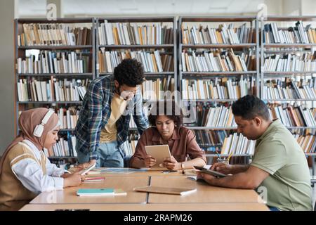 Group of students studying together in the library, they using gadgets during their teamwork Stock Photo