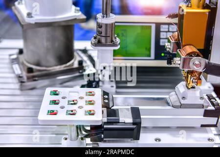 Factory machinery at work, A small printed circuit board is assembled into an automated robotic arm Stock Photo