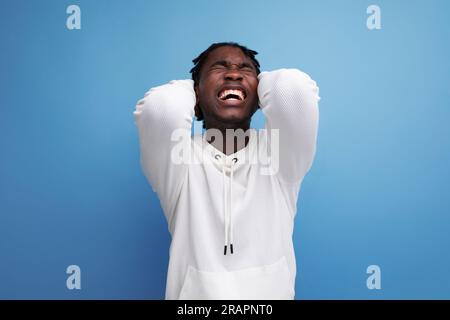 joyful energetic happy dark-skinned young brunette man in a white sweatshirt on the background with copy space Stock Photo