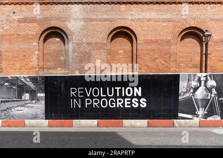 A sign in an area near the Science and Industry Museum undergoing regeneration reads, 'Revolution in Progress' in Manchester, UK. Stock Photo