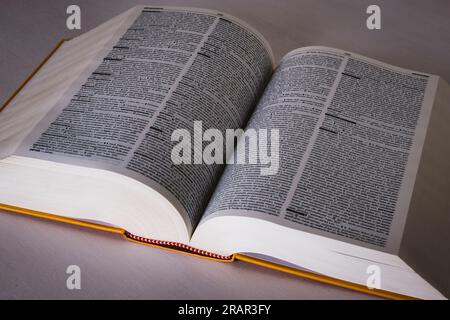 Dictionary with thousands of pages open on a white table. Stock Photo