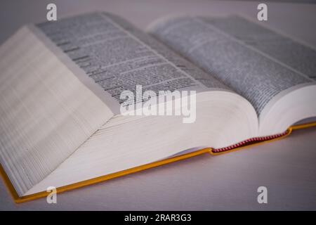 Old open dictionary framed laterally which highlights the thousands of pages that compose it. Stock Photo
