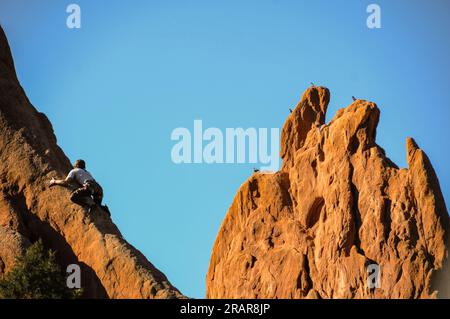 Thrill seeking male rock climber clinging to red rock slab in Garden of the Gods park, Colorado Stock Photo