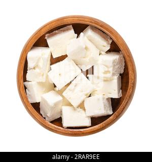 Greek feta cubes, brined cheese cut in block shape, in a wooden bowl. Cheese, matured in brine, with a soft and moist texture, and salty taste. Stock Photo