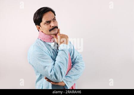 Portrait of an happy Indian farmer in rural India concept. White background, standing in a deep thinking. hand on the chin. Stock Photo