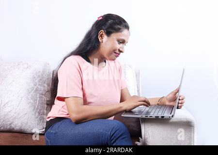 Happy Indian family of father, mother, son and daughter surfing laptop having pleasant time together joyfully. Family is looking into the laptop. Stock Photo
