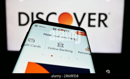 Smartphone with webpage of US company Discover Financial Services on screen in front of business logo. Focus on top-left of phone display. Stock Photo