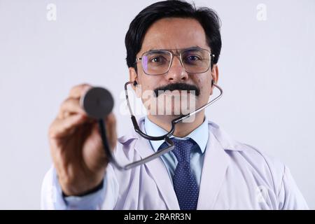 Beautiful portrait of a happy Indian female doctor in uniform wearing stethoscope and specs showing stethoscope in hand. Stock Photo