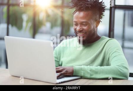Close-up of a laughing african american man looking into a laptop Stock Photo
