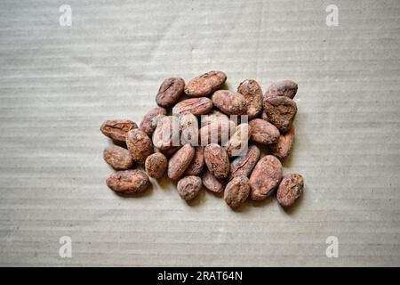 Close-up image of a pile of dry cocoa beans (seeds of the cacao tree) on a rough paper. Perfectly organic healthy superfood ready for consumption. Stock Photo
