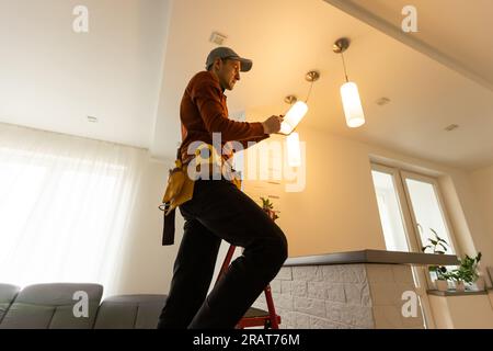 Electrician man working on exterior light, install LED replacement lamp at home. Maintenance concept. Stock Photo