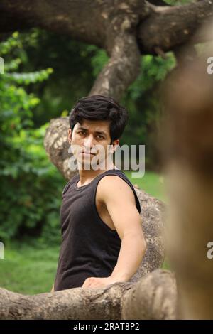 Young teen boy posing in the park in greens and serene atmosphere. Martial arts expert in city park. Stock Photo