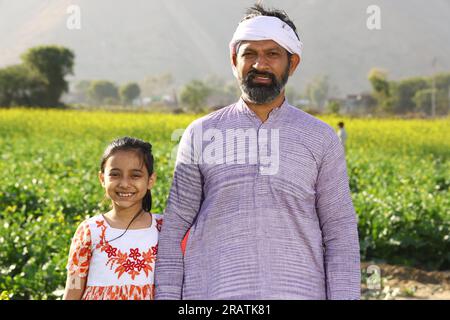 Indian rural happy farmers. Father and daughter in mustard field enjoying the flourished agriculture crops. Yellow Mustard flowers. Stock Photo