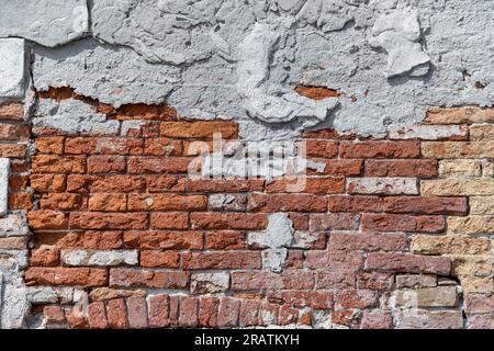 Plaster peeling from an old red brick wall. Worn out building in Venice. Stock Photo