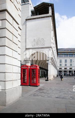 London, UK - April 19 2023: Covent Garden with the entrance to the Royal Opera House and two red telephone boxes. At the junction of James Street. Stock Photo