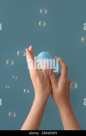 Hands with soap and bubbles on blue background Stock Photo