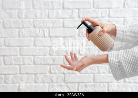 Hands with liquid soap on white brick background Stock Photo