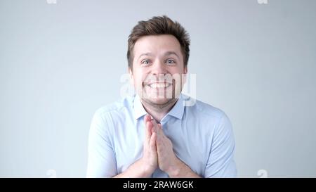 The young man, in awe, claps his hands, saying wow Stock Photo
