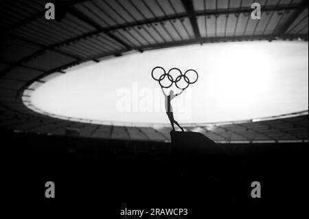 PARIS, FRANCE, JULY 7, 2023: Symbolic Power: Statue of Athletic Woman Raises Olympic Circle at Modern Olympic Stadium. Sport Photo for Paris 2024 Summ Stock Photo