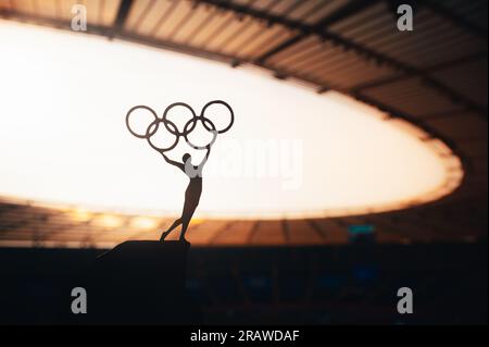 PARIS, FRANCE, JULY 7, 2023: Symbolic Power: Statue of Athletic Woman Raises Olympic Circle at Modern Olympic Stadium. Sport Photo for Paris 2024 Summ Stock Photo