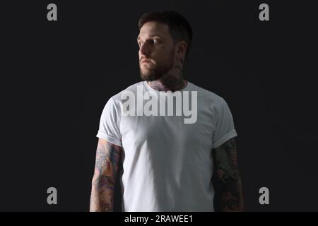 Handsome hipster man with tattoos on black background Stock Photo