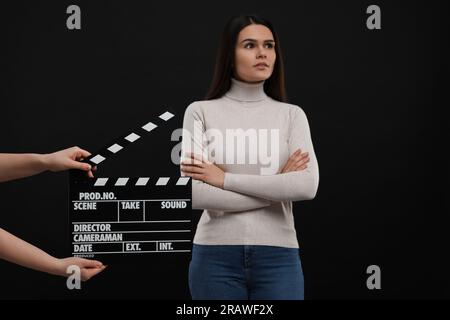 Actress performing while second assistant camera holding clapperboard on black background. Film industry Stock Photo