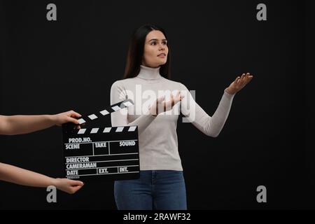 Actress performing while second assistant camera holding clapperboard on black background. Film industry Stock Photo