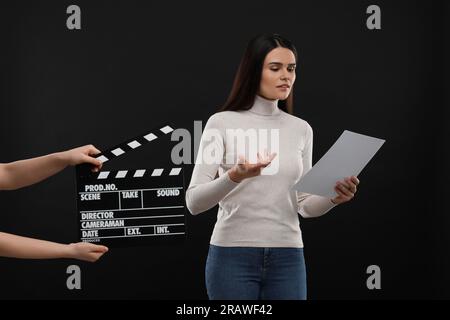 Actress performing while second assistant camera holding clapperboard on black background. Film industry Stock Photo