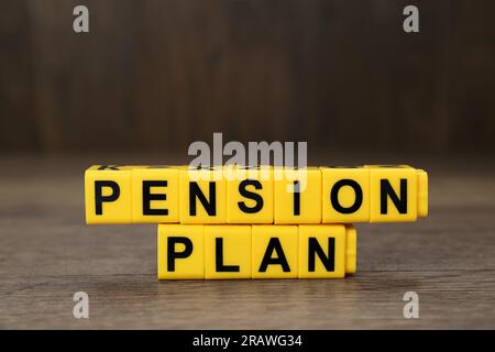 Words Pension Plan made of yellow cubes on wooden table, closeup Stock Photo