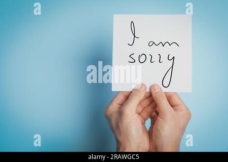 Apology. Man holding card with phrase I Am Sorry on light blue background. Space for text Stock Photo