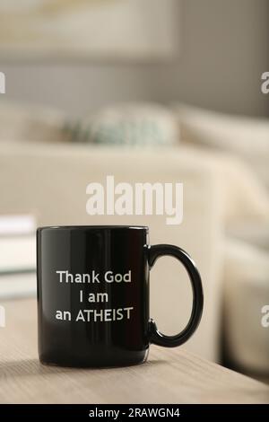 Cup with phrase Thank God I Am Atheist on wooden table Stock Photo