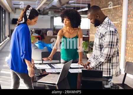 Diverse business people having meeting and discussing work, using tablet and laptop at office. Casual business, teamwork, communication and work, unal Stock Photo