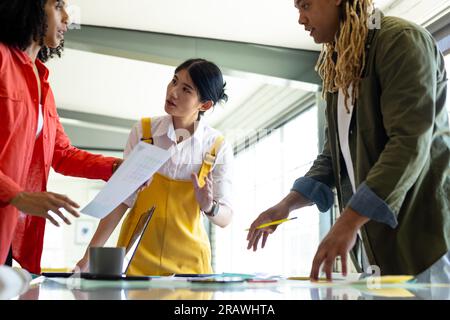 Diverse male and female creatives sitting at table discussing project in design meeting. Business, teamwork, meeting, design, creative work and casual Stock Photo