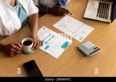 Midsection of senior african american couple using laptop and paying bills at home. Senior lifestyle, finance, retirement and domestic life, unaltered Stock Photo
