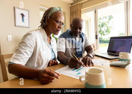 Senior african american couple sitting at table using laptop and paying bills at home. Senior lifestyle, finance, retirement and domestic life, retire Stock Photo