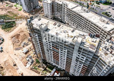 busy construction site with residential building under construction and working crane. aerial drone view. Stock Photo