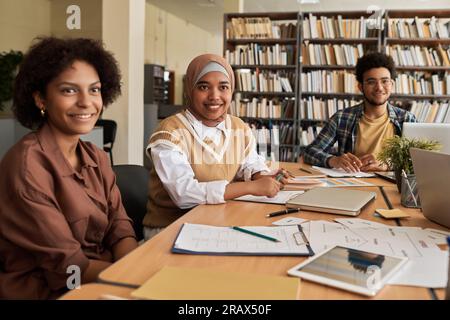 Group of students studying foreign language together in class, they sitting at table with textbooks and computers Stock Photo