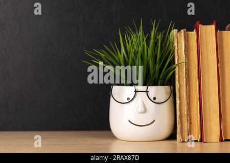 Old books on a table, potted plant with face and glasses and copy space for your text Stock Photo