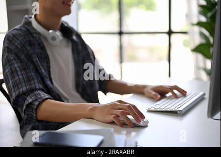 Close-up image of a male programmer or freelancer in a flannel shirt using his computer and working on his project on a computer in the office. Stock Photo