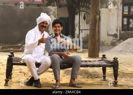 Happy rural Indian family in village Aspirational family sitting with a bank manager who is showing thumbs up. Stock Photo