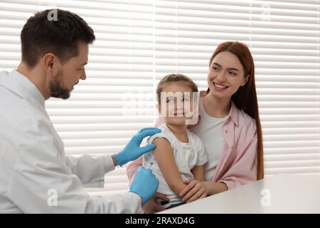 Children's hepatitis vaccination. Mother with her daughter in clinic. Doctor giving injection to little girl Stock Photo
