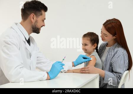 Children's hepatitis vaccination. Mother with her daughter in clinic. Doctor giving injection to little girl Stock Photo